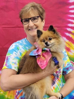 Staff member holding a small dog in a colorful shirt