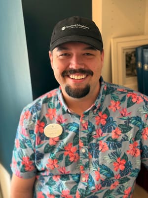 Staff member smiling in floral shirt indoors