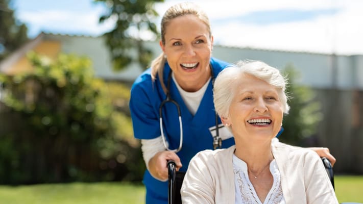 A nurse smiling with a resident in a garden