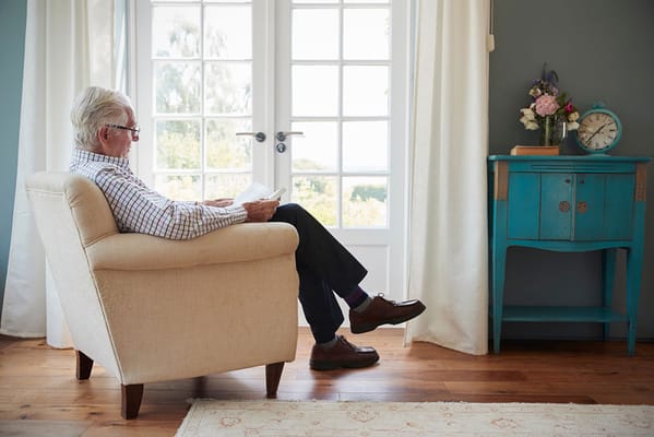 An older man reading in a cozy armchair