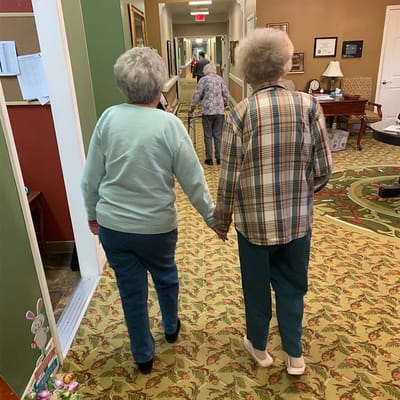 Two residents walking hand in hand down a hallway