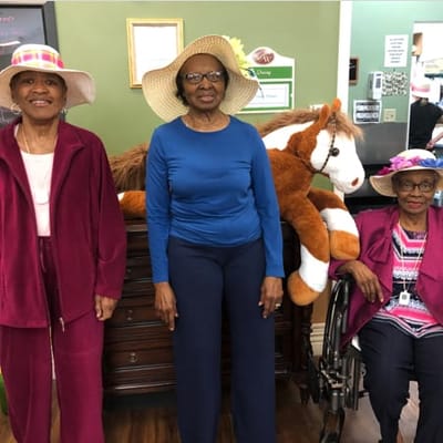 Residents posing with a stuffed horse and wearing hats