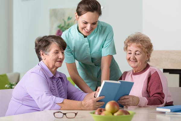 Residents reading a book with staff assistance