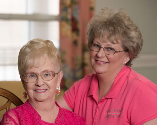 Two residents smiling together in the facility's activity room.