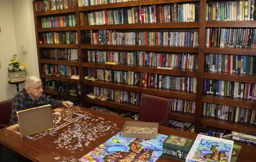 Resident assembling a puzzle in a library