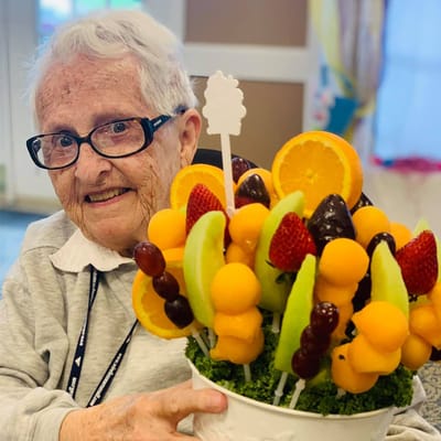 Senior resident enjoying a colorful fruit arrangement