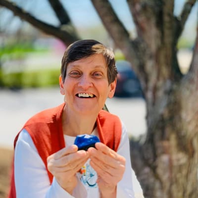 A resident smiling while holding a blue object outdoors