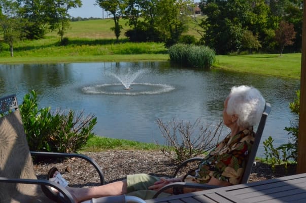 Elderly woman enjoying a serene outdoor pond view
