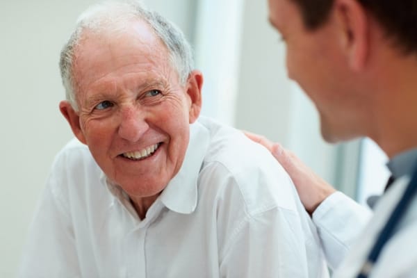 A senior man smiling during a consultation with a caregiver