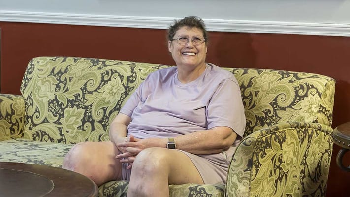 Resident smiling on a comfortable couch in a common area