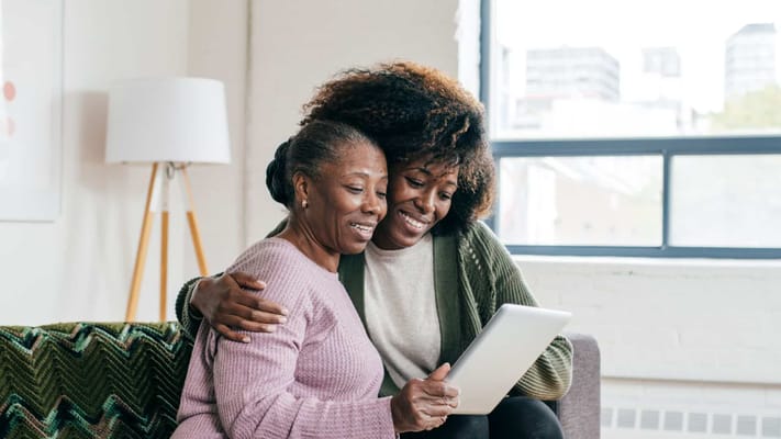 Two women sharing a moment with a tablet in a cozy interior