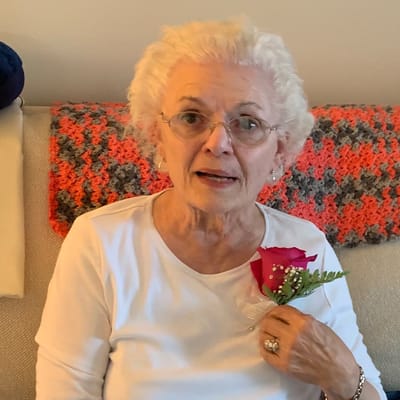 Senior resident with a rose boutonniere sitting indoors