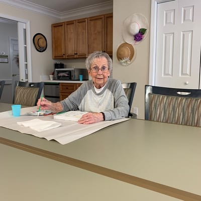 Resident painting at a table in the common area
