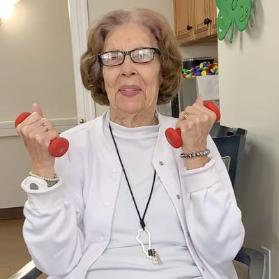 Senior resident exercising with red weights