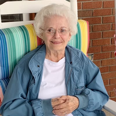 An elderly woman posing in a colorful rocking chair