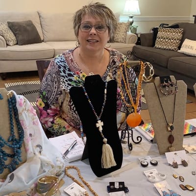 Staff member showcasing handmade jewelry in an activity room