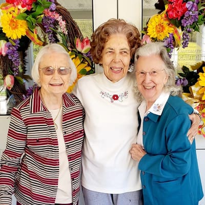 Three smiling residents together outdoors