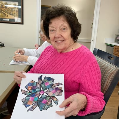 Resident proudly holding a craft project in an activity room
