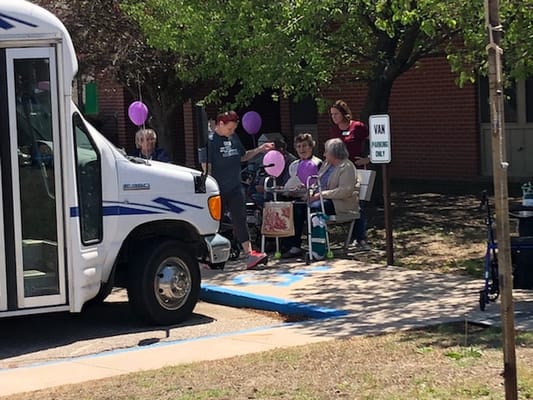 Residents enjoying an outdoor event with a facility van