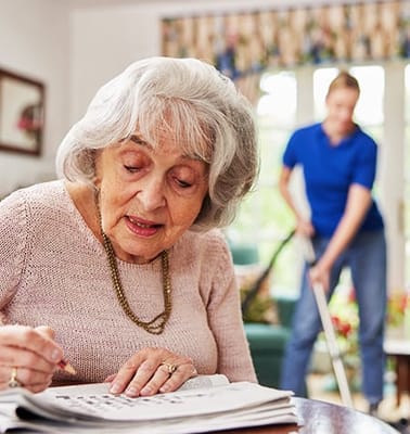 Resident engaged in an activity indoors, with staff in the background