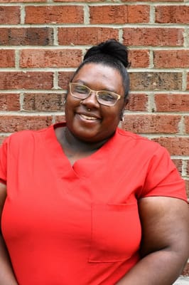 Staff member smiling in front of a brick wall