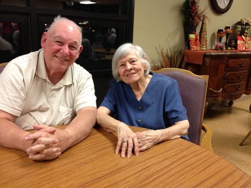 Two residents smiling at a table in a common area