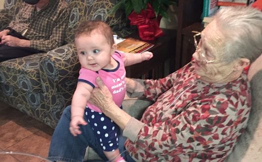 An elderly woman interacting with a baby in a cozy common area