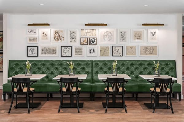 Interior dining area with green booths and art on the wall