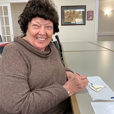 Resident happily painting at a table in an activity room