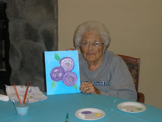 An elderly woman holding her painting in an art activity