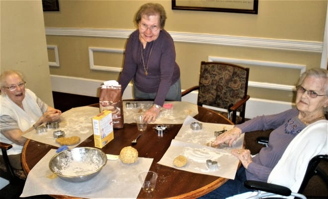 Residents baking together at a table in the facility
