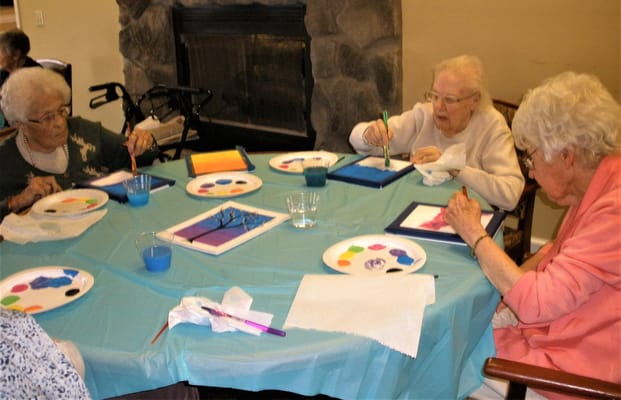 Residents engaged in a painting activity around a table