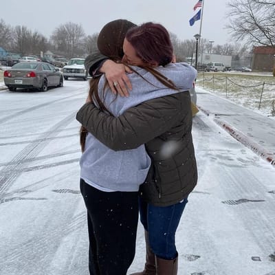 Two women embracing in the snow outside