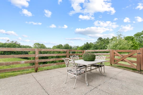 Outdoor patio with table and chairs overlooking green space