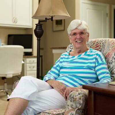 A smiling resident sitting in a cozy living room chair