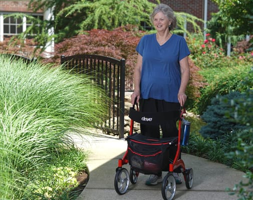 Resident enjoying the outdoor garden space with a mobility aid