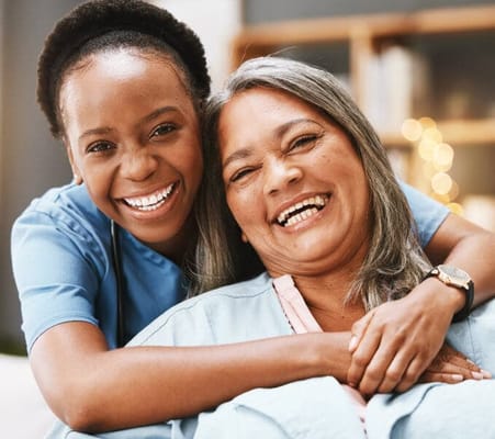 A caregiver and resident smiling together in a common area
