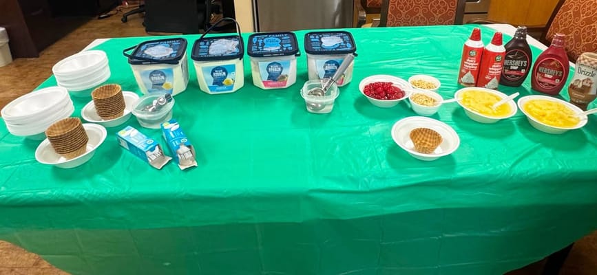 A dessert table with ice cream and toppings at a facility event