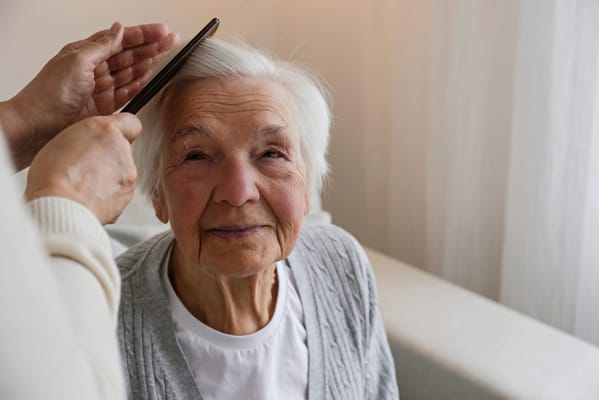 A caregiver combing the hair of an elderly woman