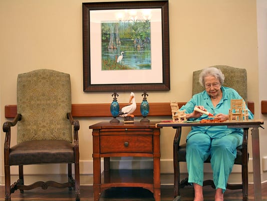 An elderly woman playing with toys in a common area