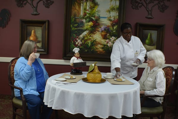 A staff member serving food to residents in a common area