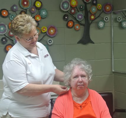 Staff member styling resident's hair in a common area