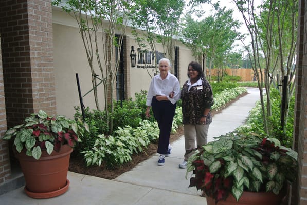 A resident and staff member walking in a garden area