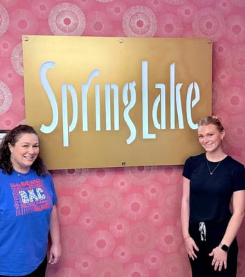 Staff members beside the facility logo inside