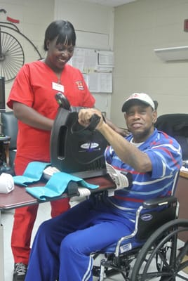 Staff assisting a resident with exercise equipment