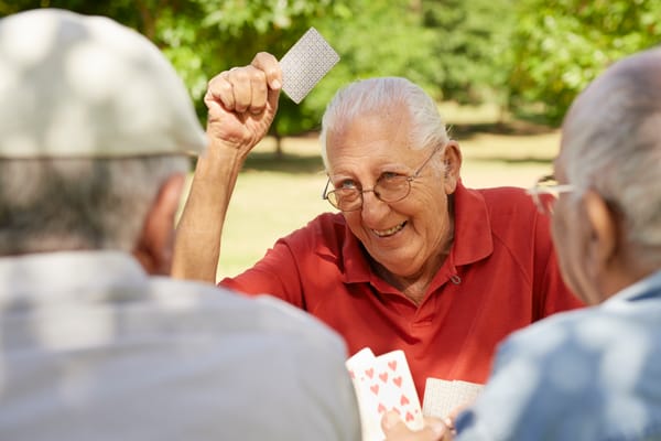 Seniors playing cards outdoors in a garden setting