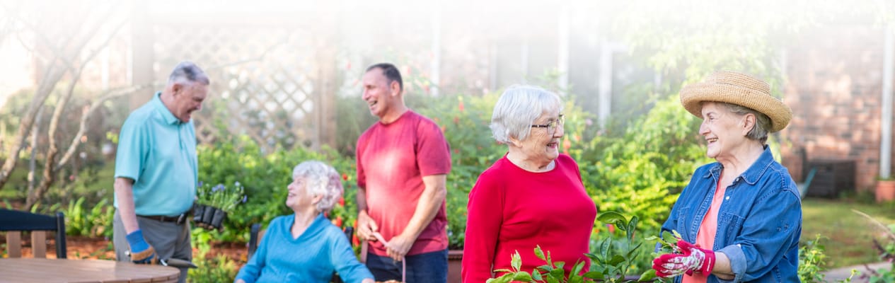 Residents and staff gardening in a pleasant outdoor space