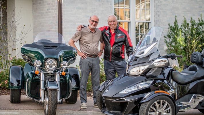 Two residents standing beside motorcycles outdoors
