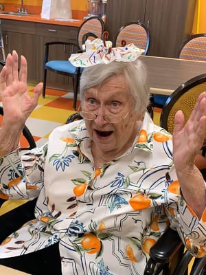An enthusiastic resident with a creative hat in an activity room