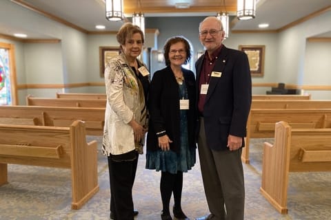 Three residents pose together in a common area
